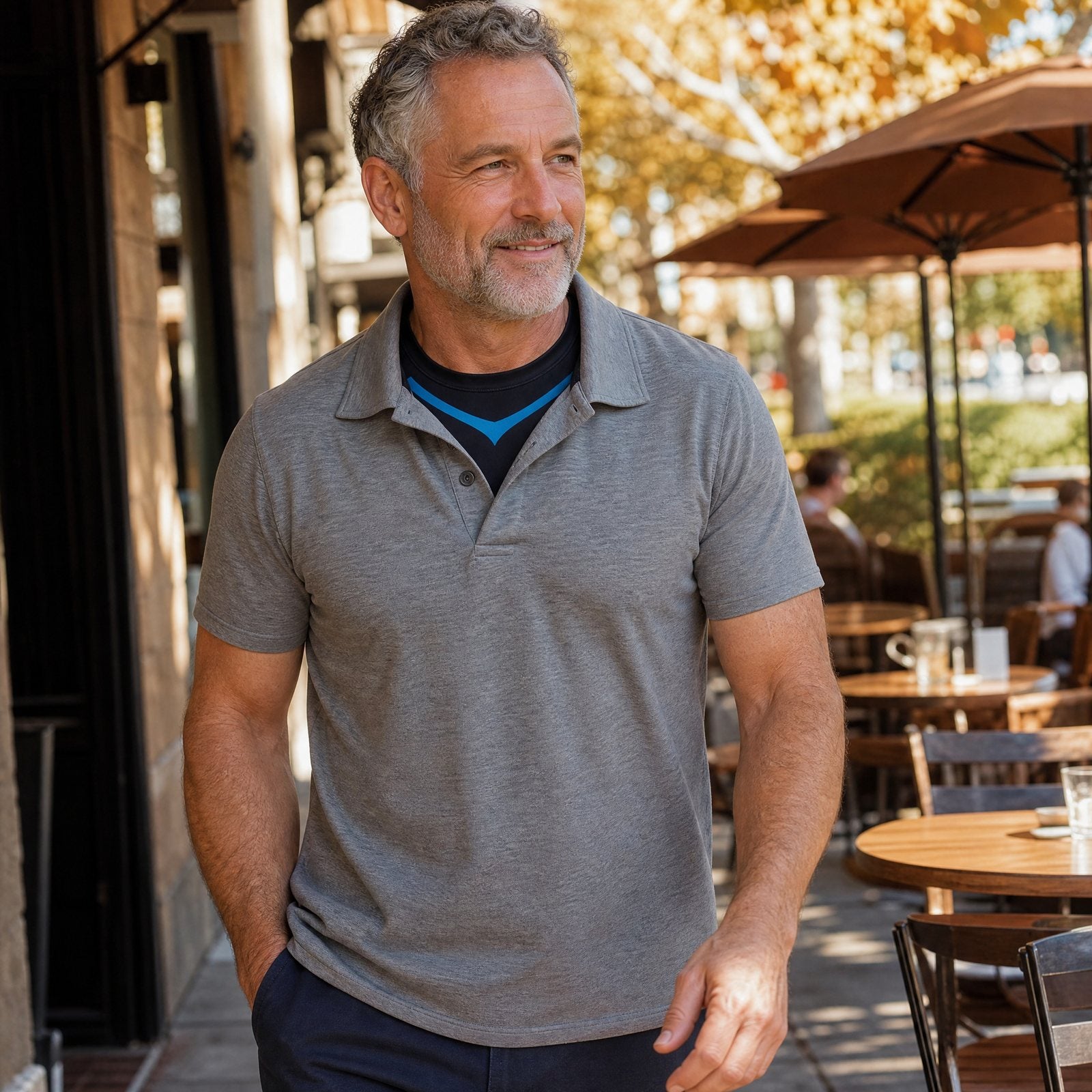 Man in a polo at a sunny cafe terrace wearing the DEFYNMEN compression tank underneath